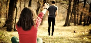 girl sitting on the ground reaching for her spouse who is walking away