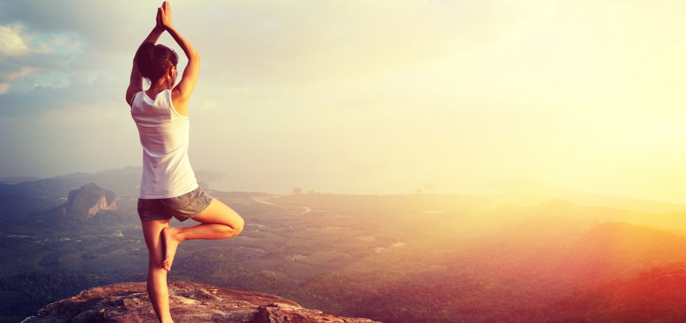 girl on rock being active doing yoga 